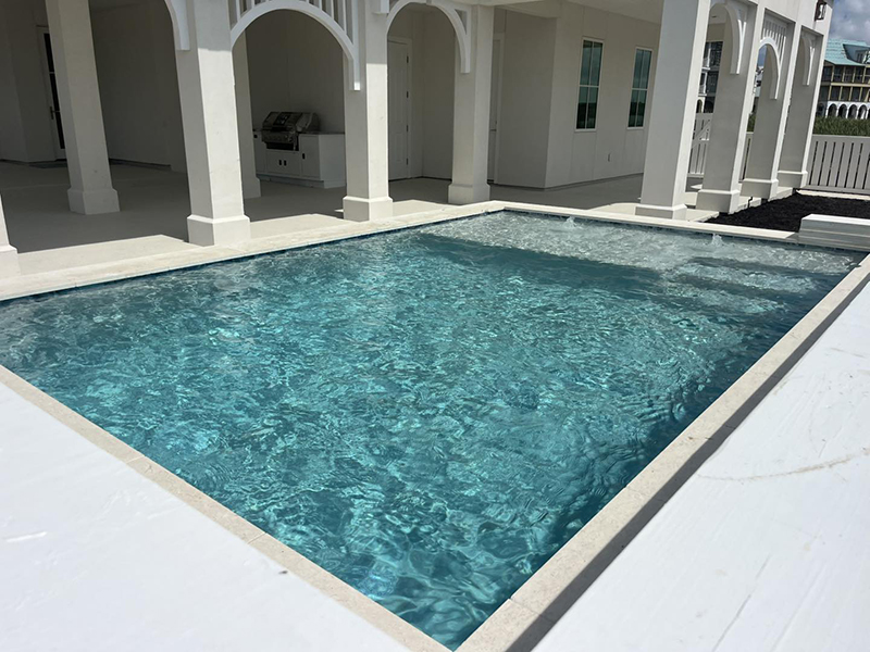 new-pool-construction-gallery-05 A clear, blue swimming pool next to a white building with arched supports.